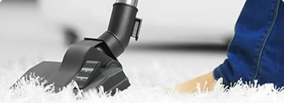 Close-up of a professional vacuuming a white carpet in Greenwood.