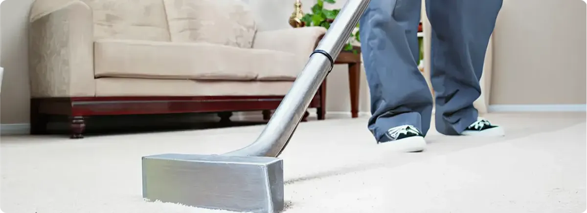 Carpet cleaning technician using a hot-water extraction wand on a light-colored carpet in a living room, Indianapolis, IN.